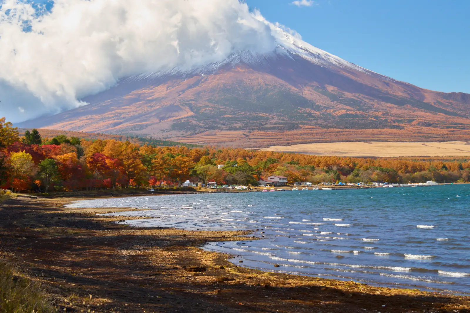 Mount Fuji above the shore of Lake Yamanaka with autumn trees in the foreground