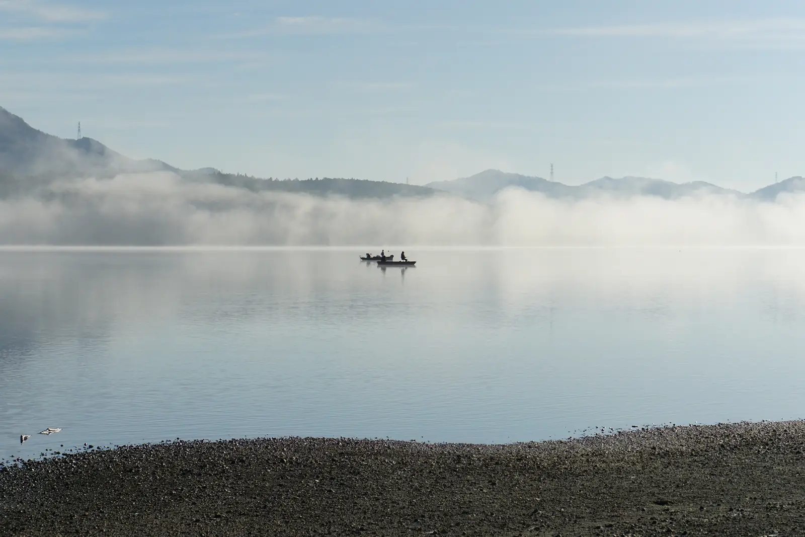 Morning mist over Lake Yamanaka with a small fishing boat on the water